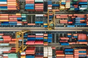 Aerial view of shipping containers and cranes at a busy port, symbolising import and export flows.