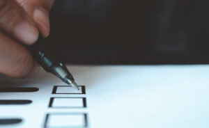 man-holding-pen-mark-vote-paper-300x184.jpg