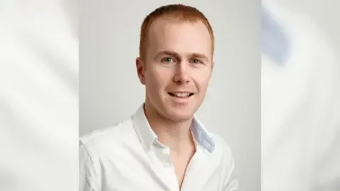 Handout Close up of Mr Freeman who has red hair and blue eyes. He is wearing a white shirt and stood in front of a white background. Handout Close up of Mr Freeman who has red hair and blue eyes. He is wearing a white shirt and stood in front of a white background.